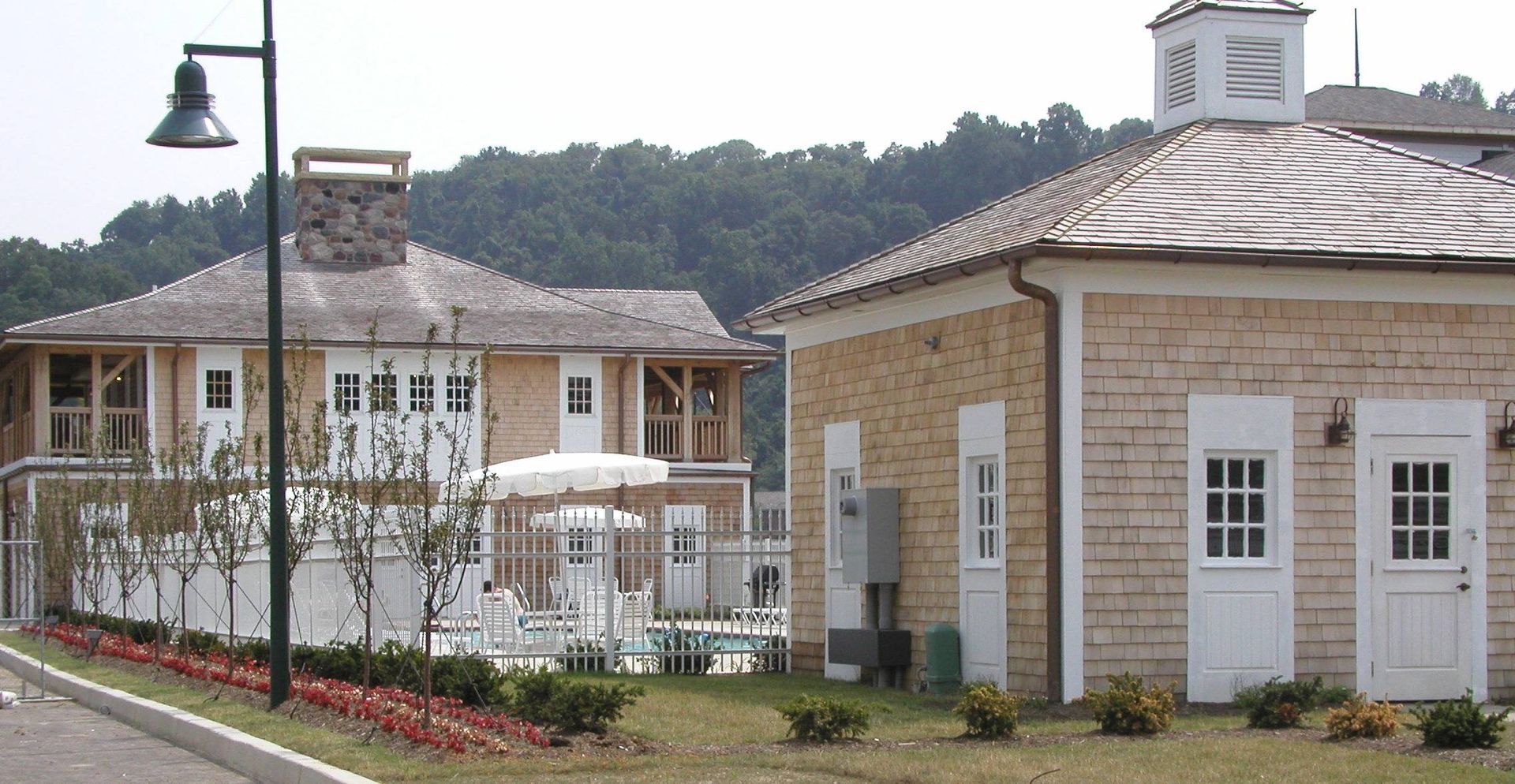Two-story stone building with white trim, patio umbrellas, and a lamp post along a street