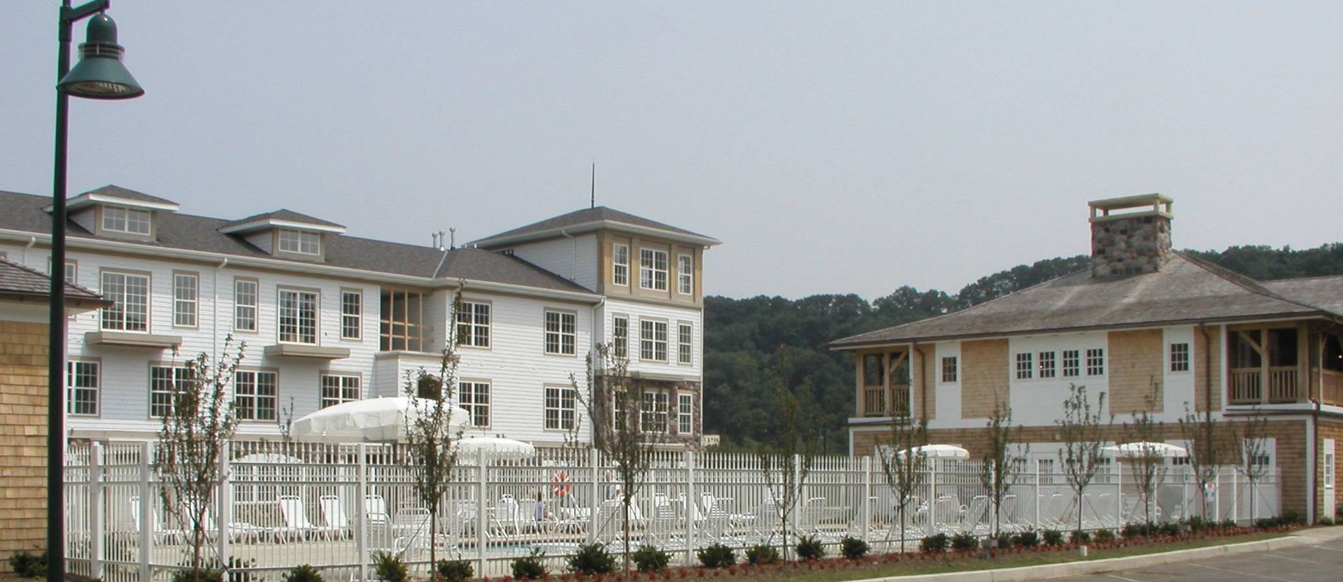 Row of white two-story houses with balconies behind a white fence on a cloudy day