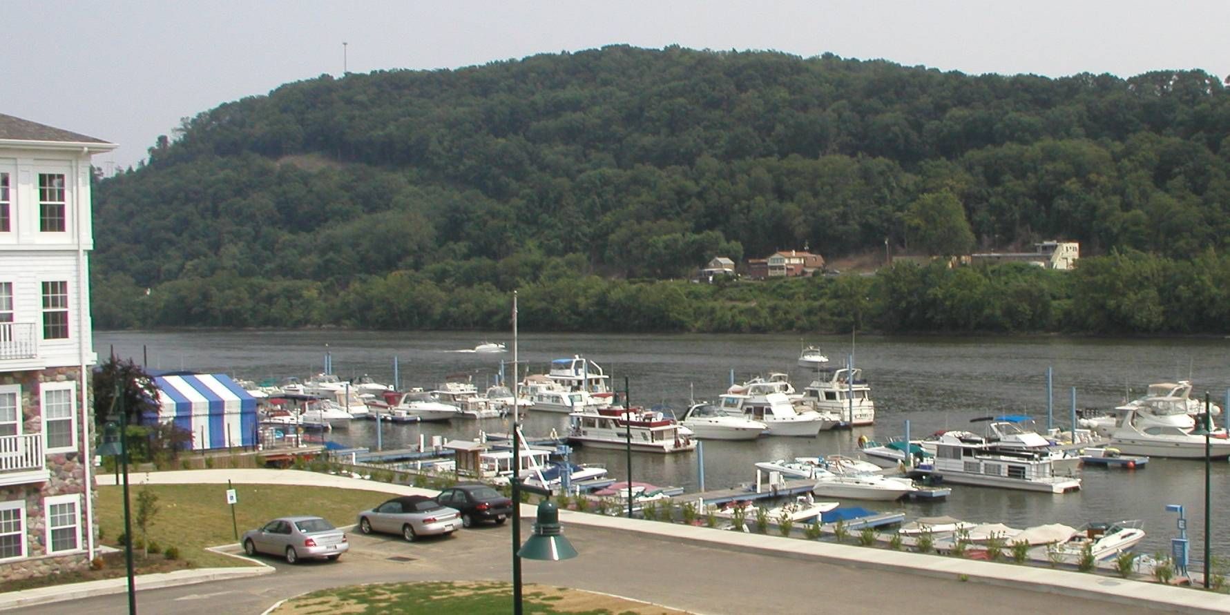 Harbor marina with many boats, a grassy shoreline, and hills in the background