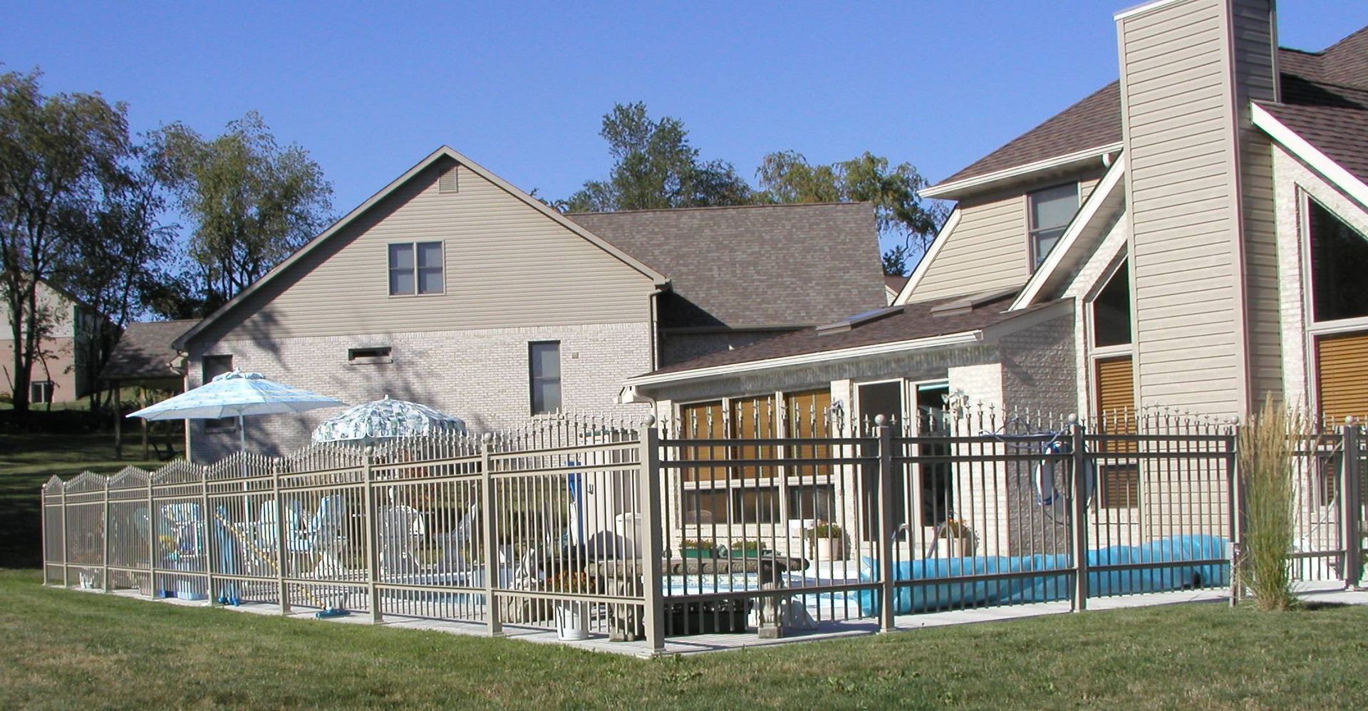 Apartment building with fenced outdoor pool and patio area on a sunny day
