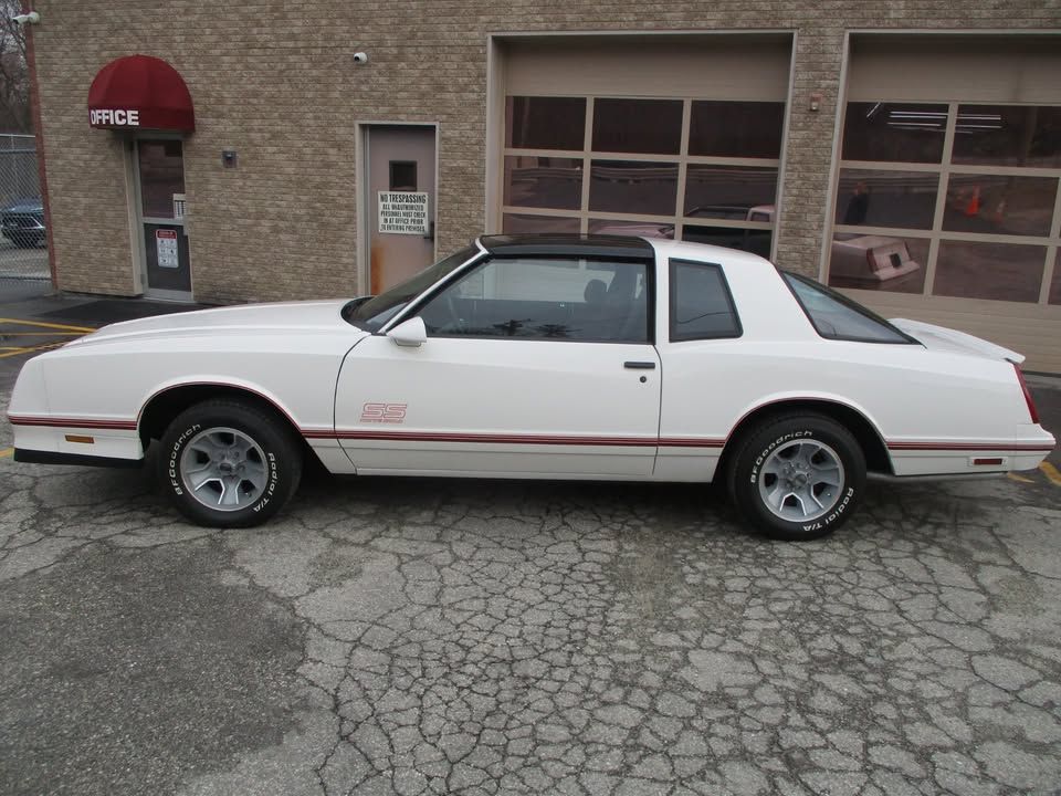 A white car is parked in front of a garage.