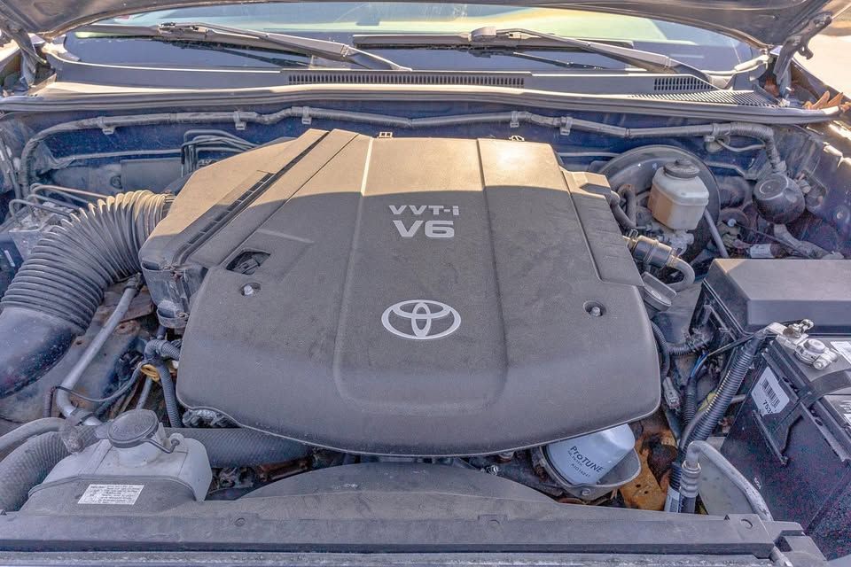 The engine of a toyota truck is shown with the hood up.