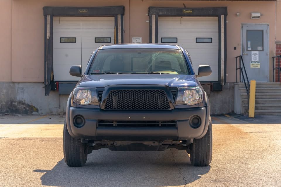 A black truck is parked in front of a warehouse.