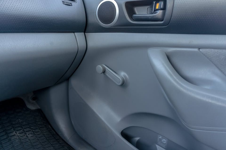 A close up of a car door with a window crank.