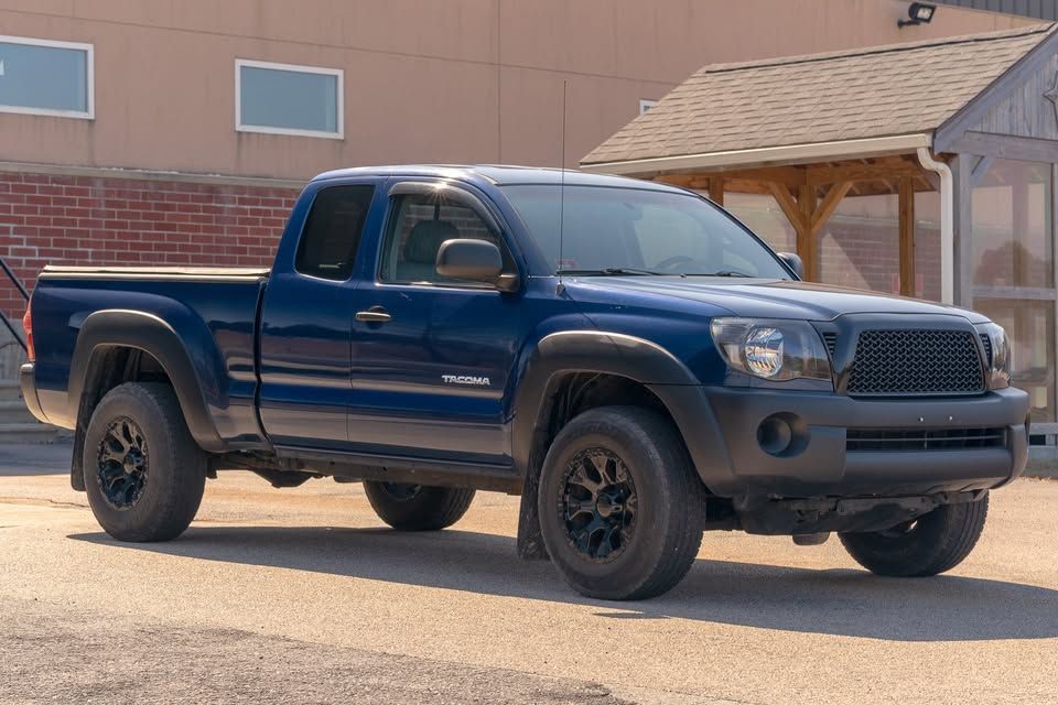 A blue truck is parked in front of a building.