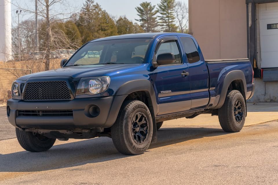 A blue toyota tacoma truck is parked in a parking lot.