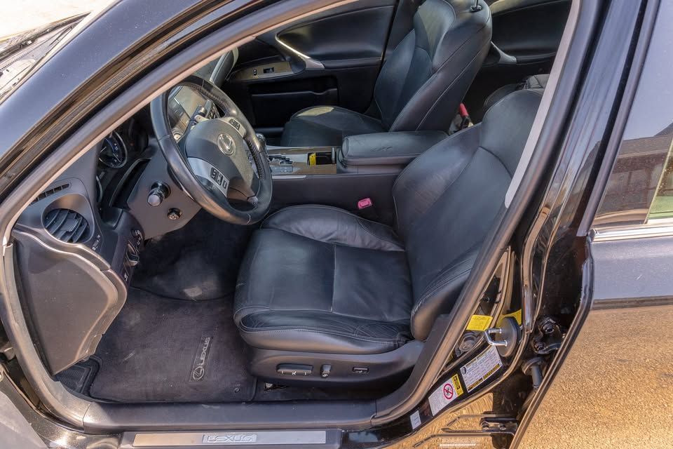 The interior of a black car with the door open and the seats up.