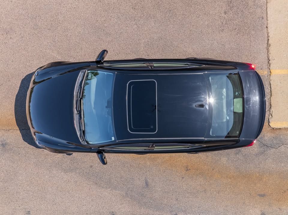 An aerial view of a black car parked in a parking lot.