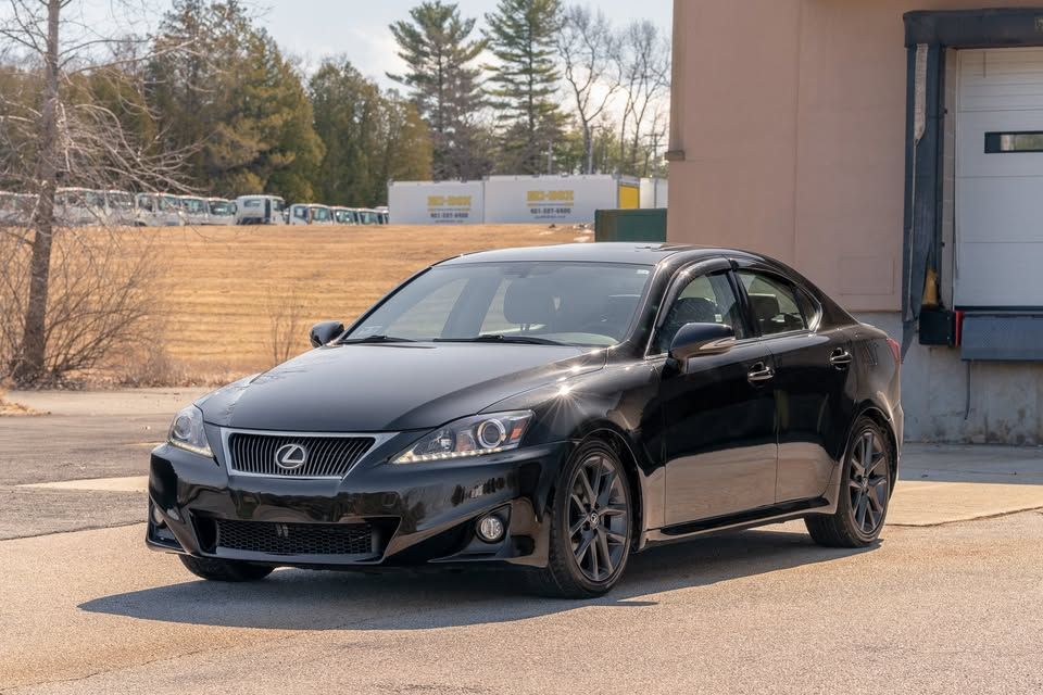 A black lexus is250 is parked in front of a building.