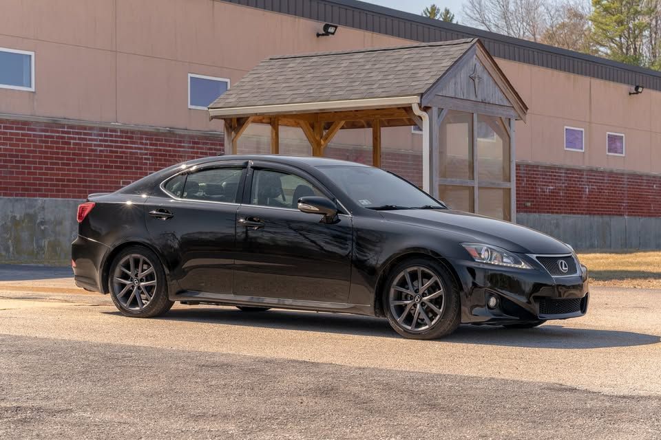 A black car is parked in front of a building.
