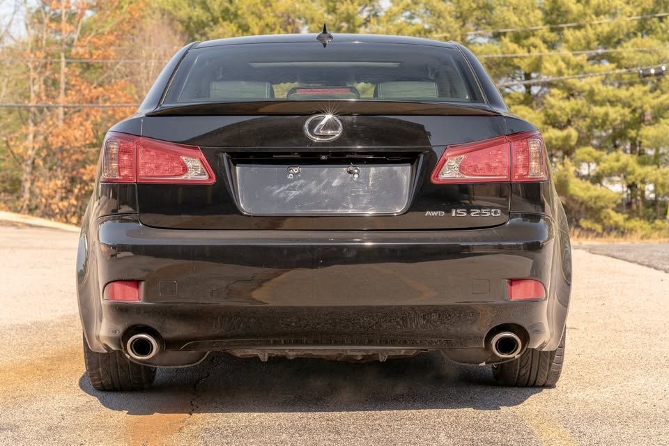 The rear end of a black lexus is parked on the side of the road.