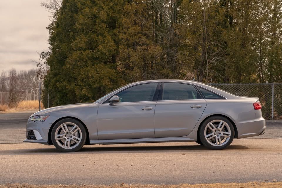 A silver audi a6 is parked on the side of the road.