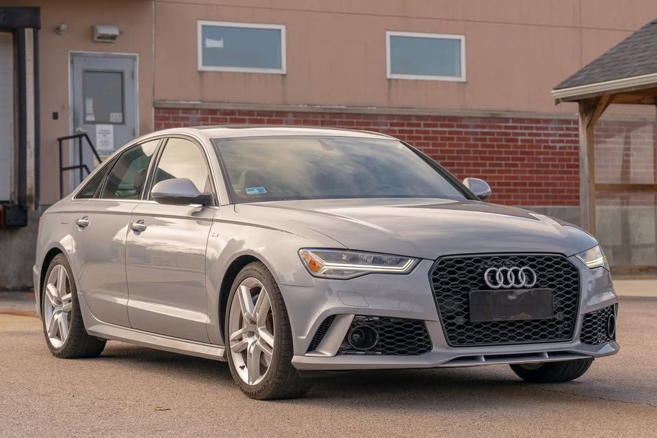 A silver audi a6 rs is parked in front of a brick building.