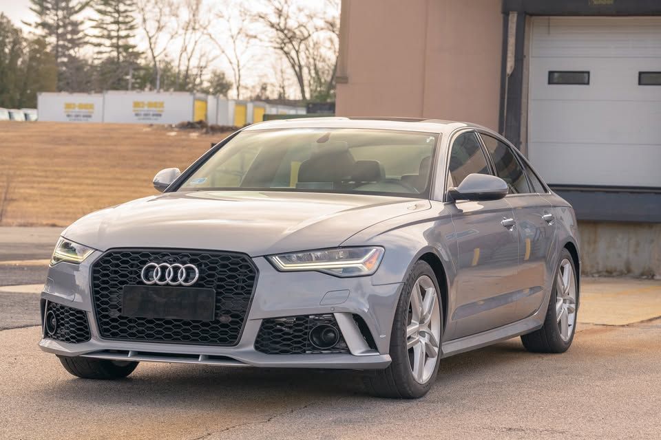 A gray audi a6 is parked in front of a garage door.