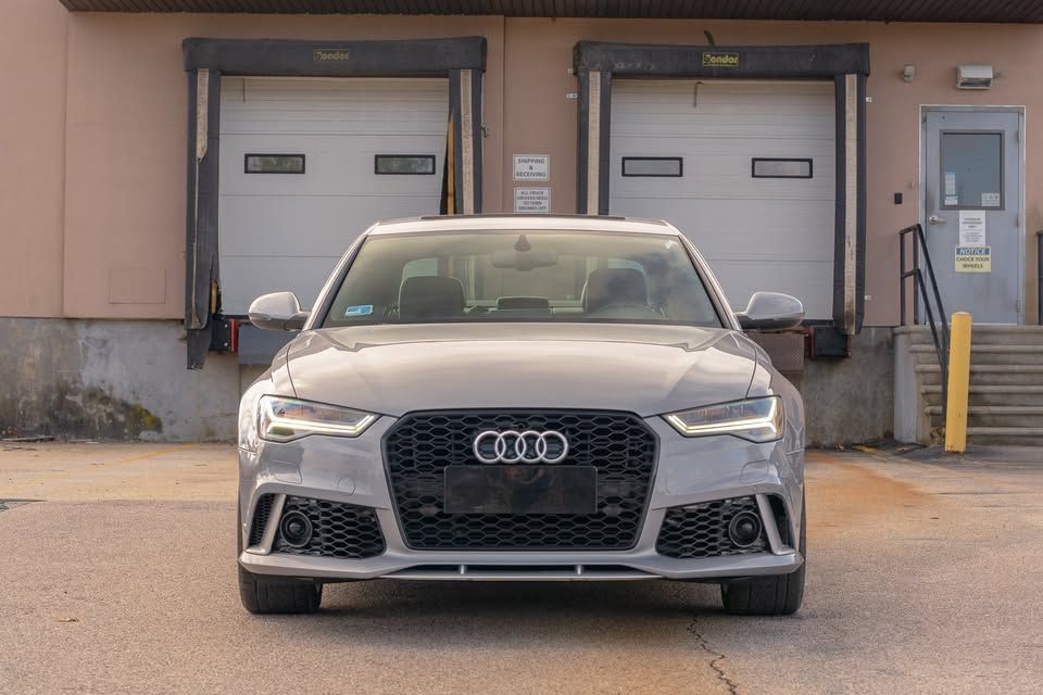 A silver audi rs6 is parked in front of a warehouse.