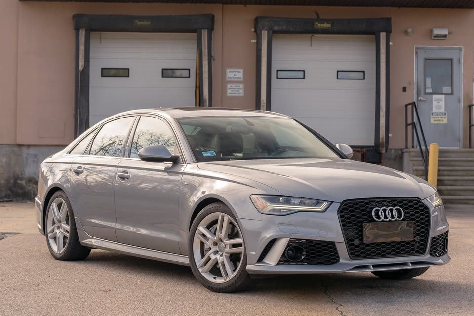 An audi a6 rs is parked in front of a warehouse.
