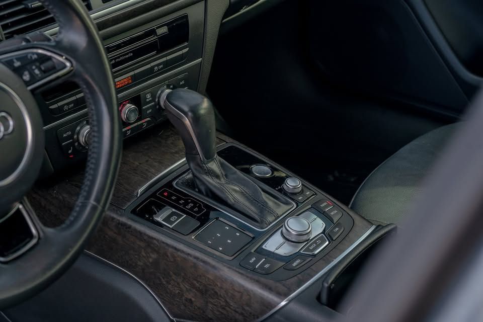 The interior of a car with a steering wheel and a shifter.