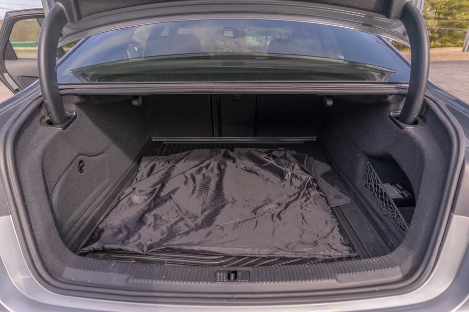 The trunk of a car with a black mat in it.