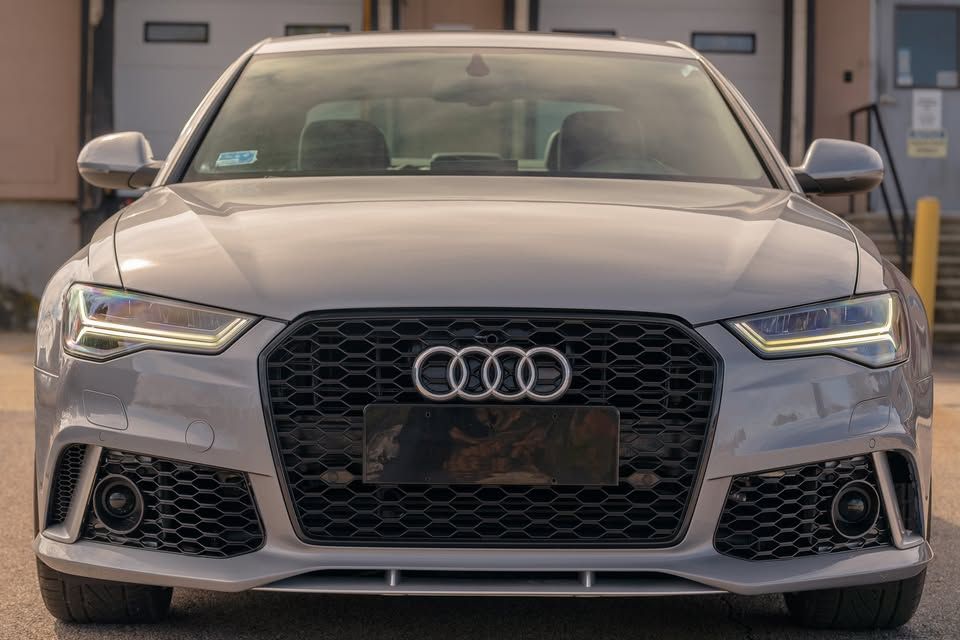 A silver audi rs6 is parked in front of a building.
