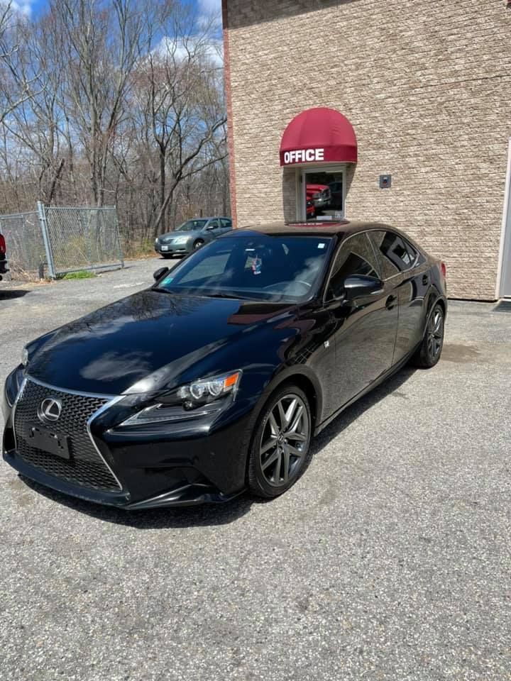 A black Lexus is parked in front of a brick building