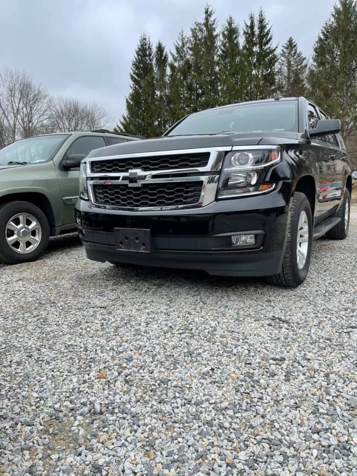 A black SUV is parked in a gravel lot