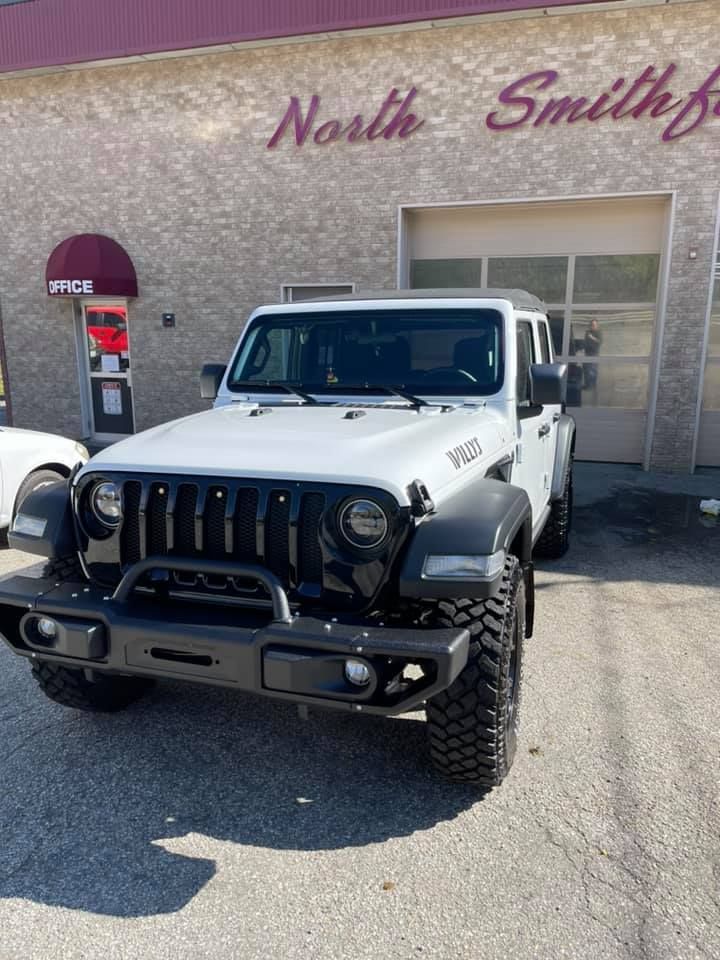 A white Jeep is parked in front of a building