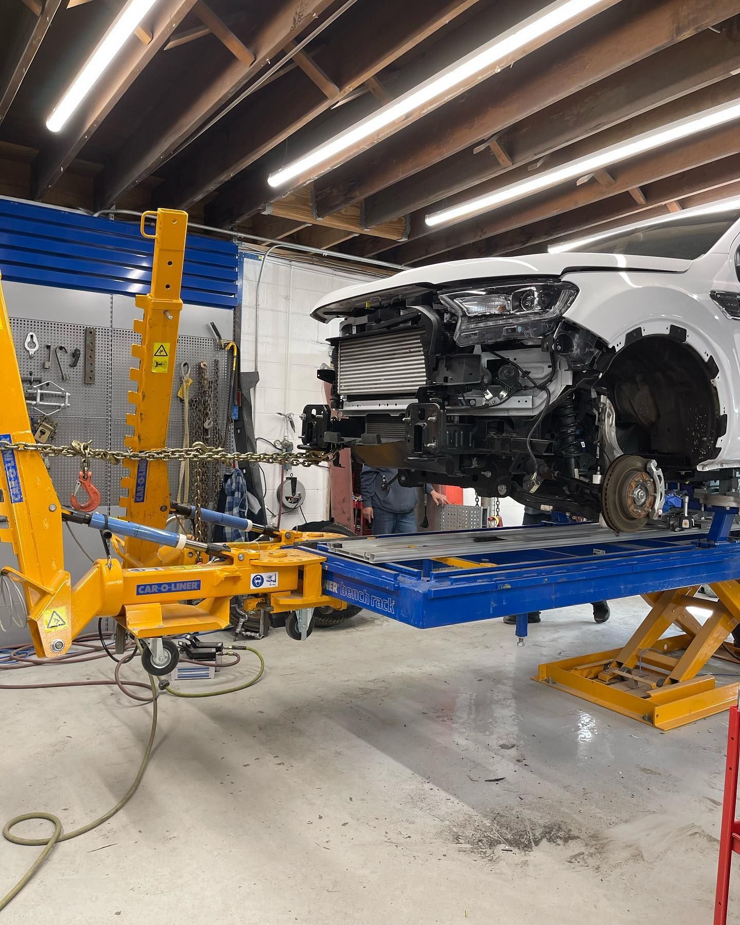 A white car is being worked on in an auto shop