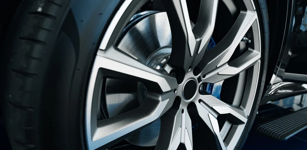 Close-up of a silver alloy car wheel with a black tire and blue brake caliper