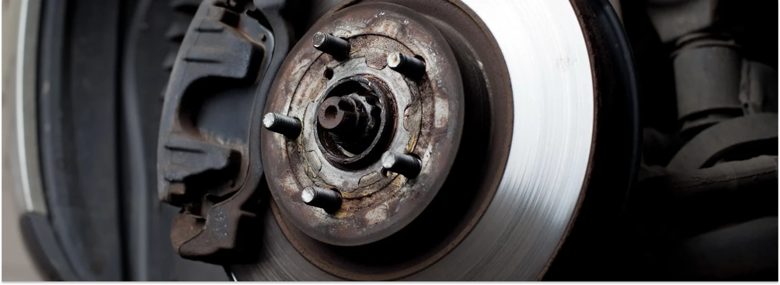 Close-up of a car brake rotor and wheel hub with visible rust and brake caliper