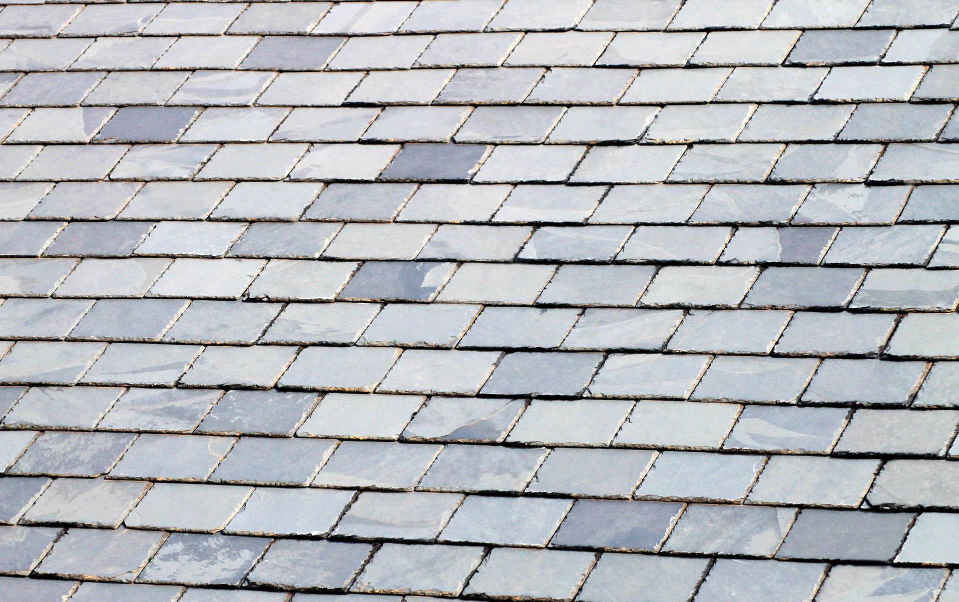 Close-up view of a roof covered with gray slate tiles arranged in a staggered pattern.