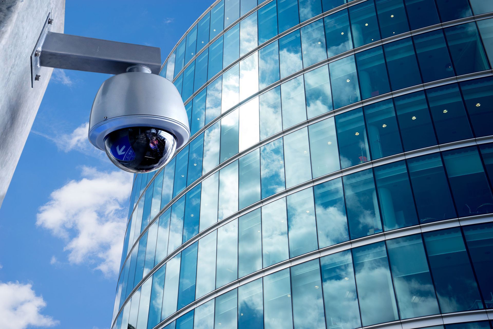 Blue security camera mounted outside a modern glass office building