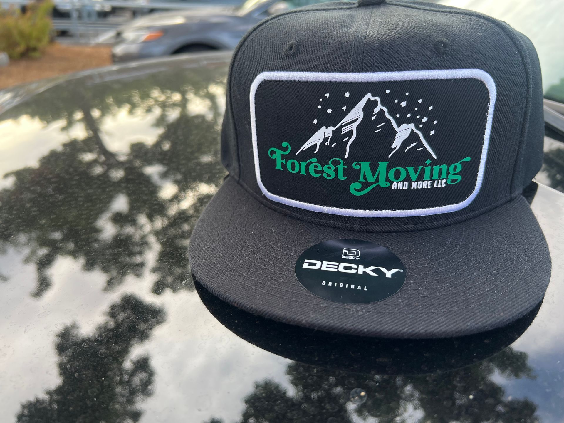 Black baseball cap with a mountain logo; on a car hood.