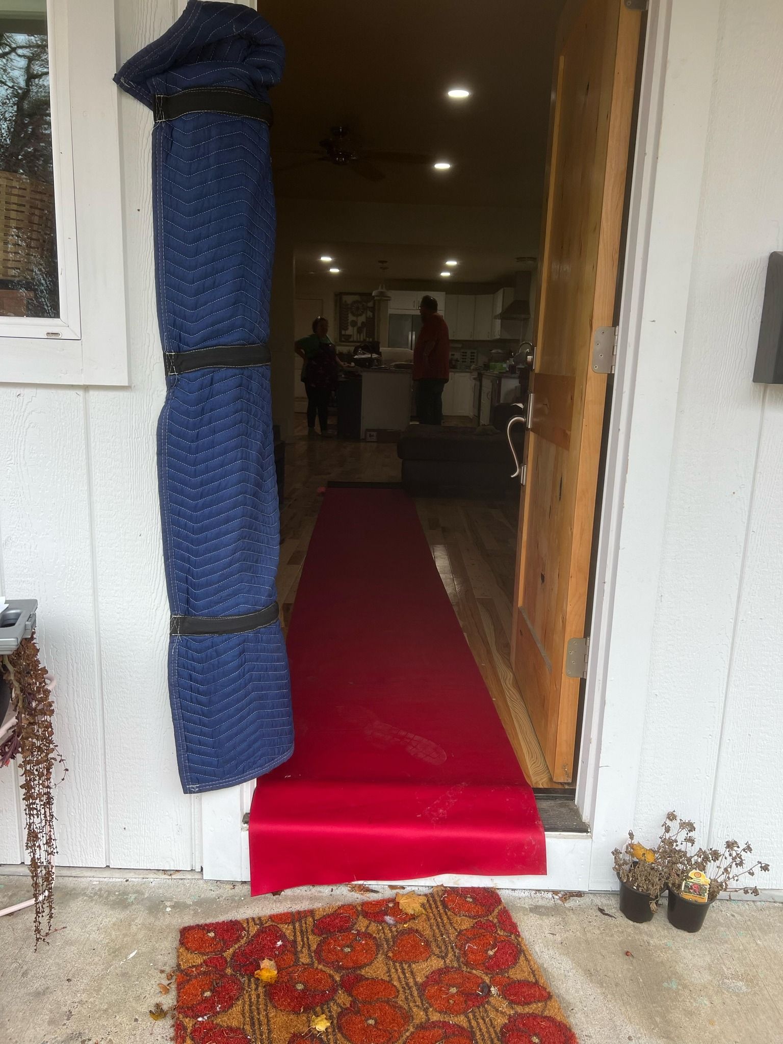Red carpet leading into a home's open doorway. A blue fabric is rolled up next to the door.