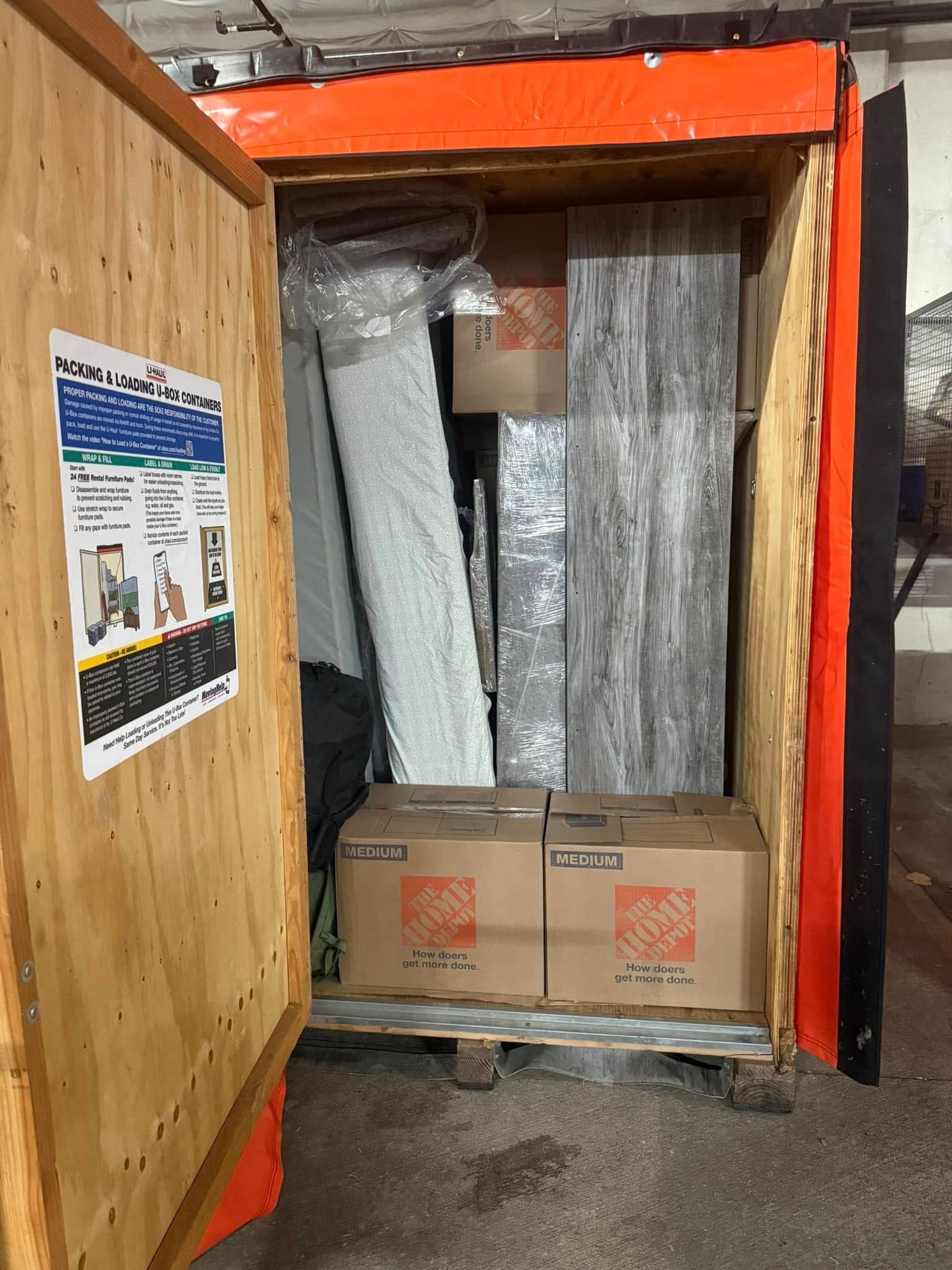 Open, orange storage container packed with boxes and wrapped furniture.