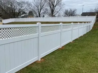 A white vinyl fence with a lattice design is sitting on top of a lush green lawn.
