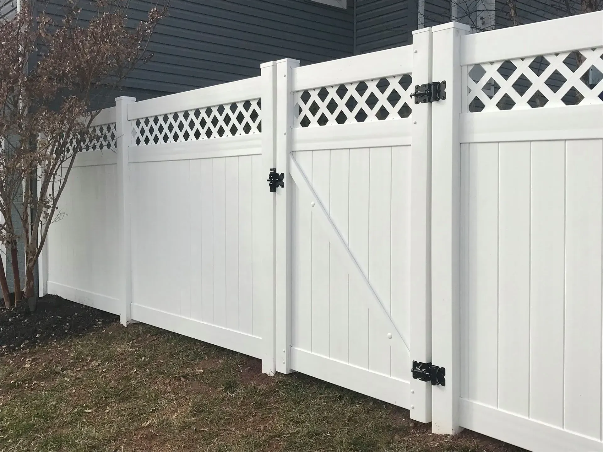 A white vinyl fence with a gate in front of a house.