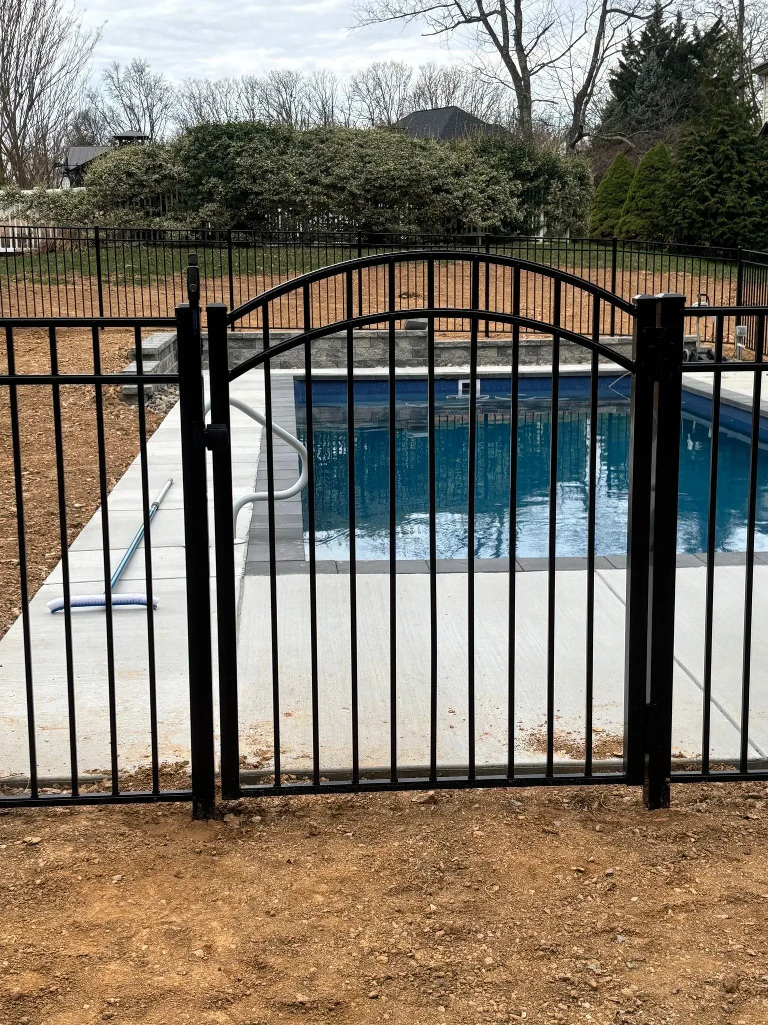 A black metal fence surrounds a swimming pool.