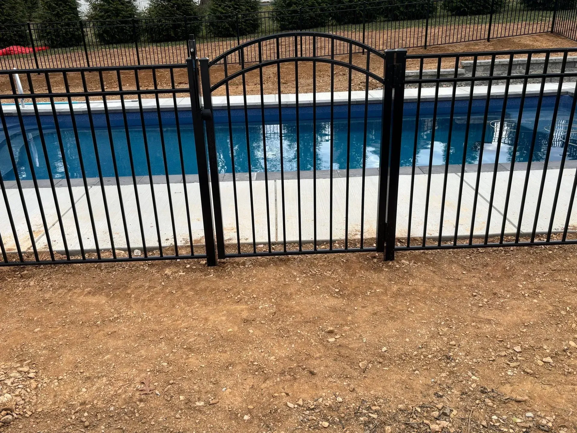 A black metal fence surrounds a swimming pool.
