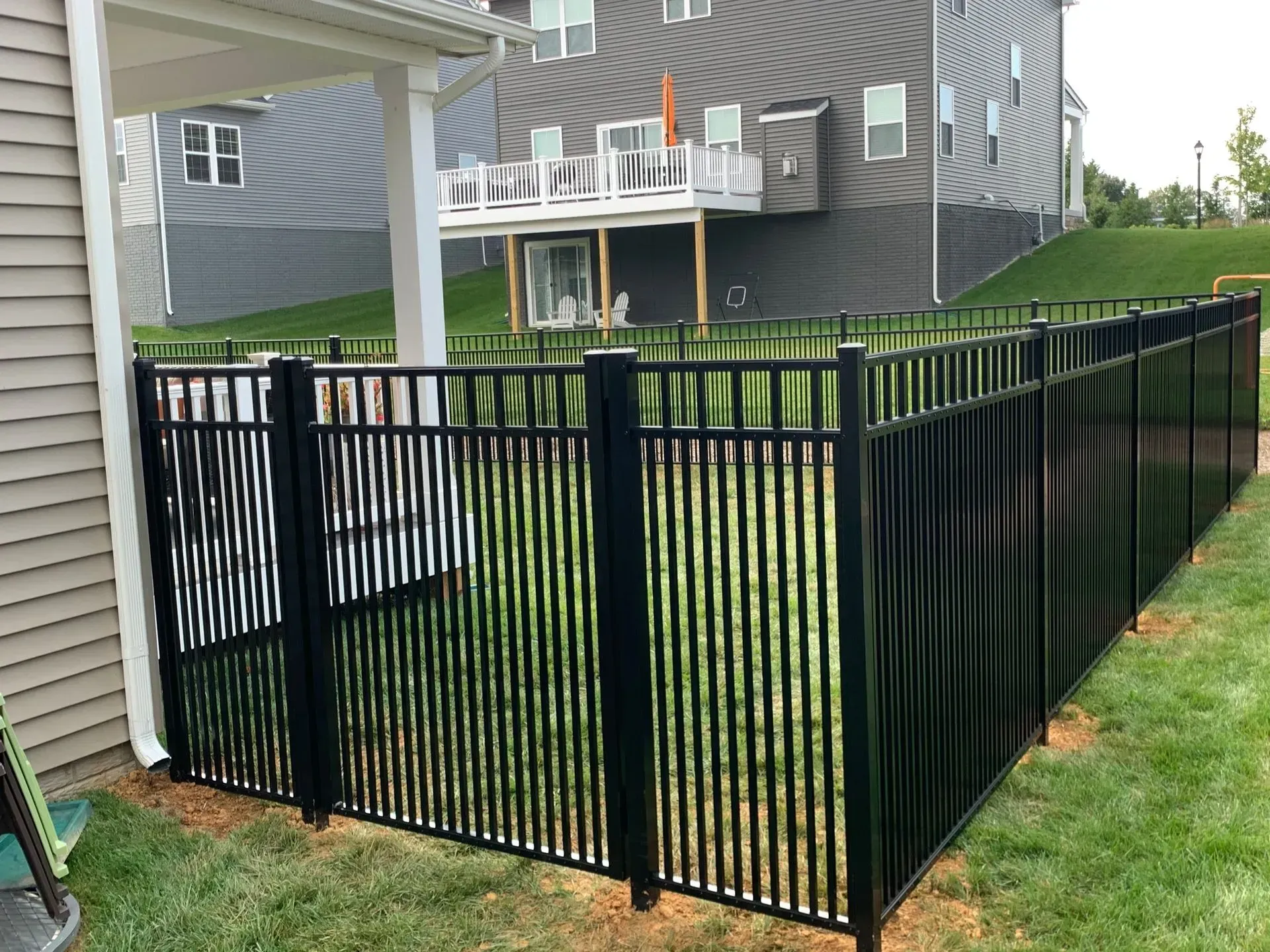 A black fence is in the backyard of a house.