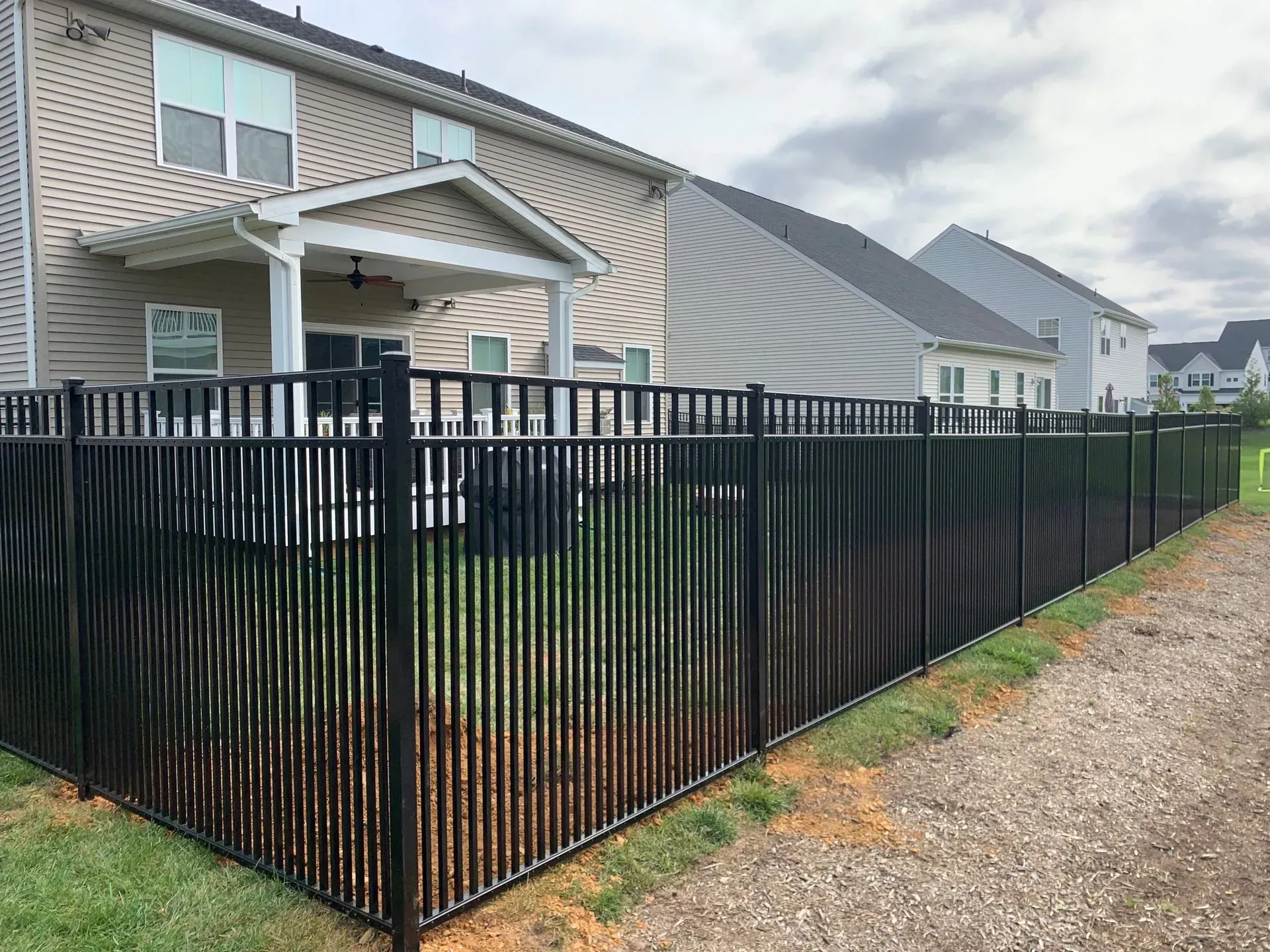 A black fence surrounds the backyard of a house.