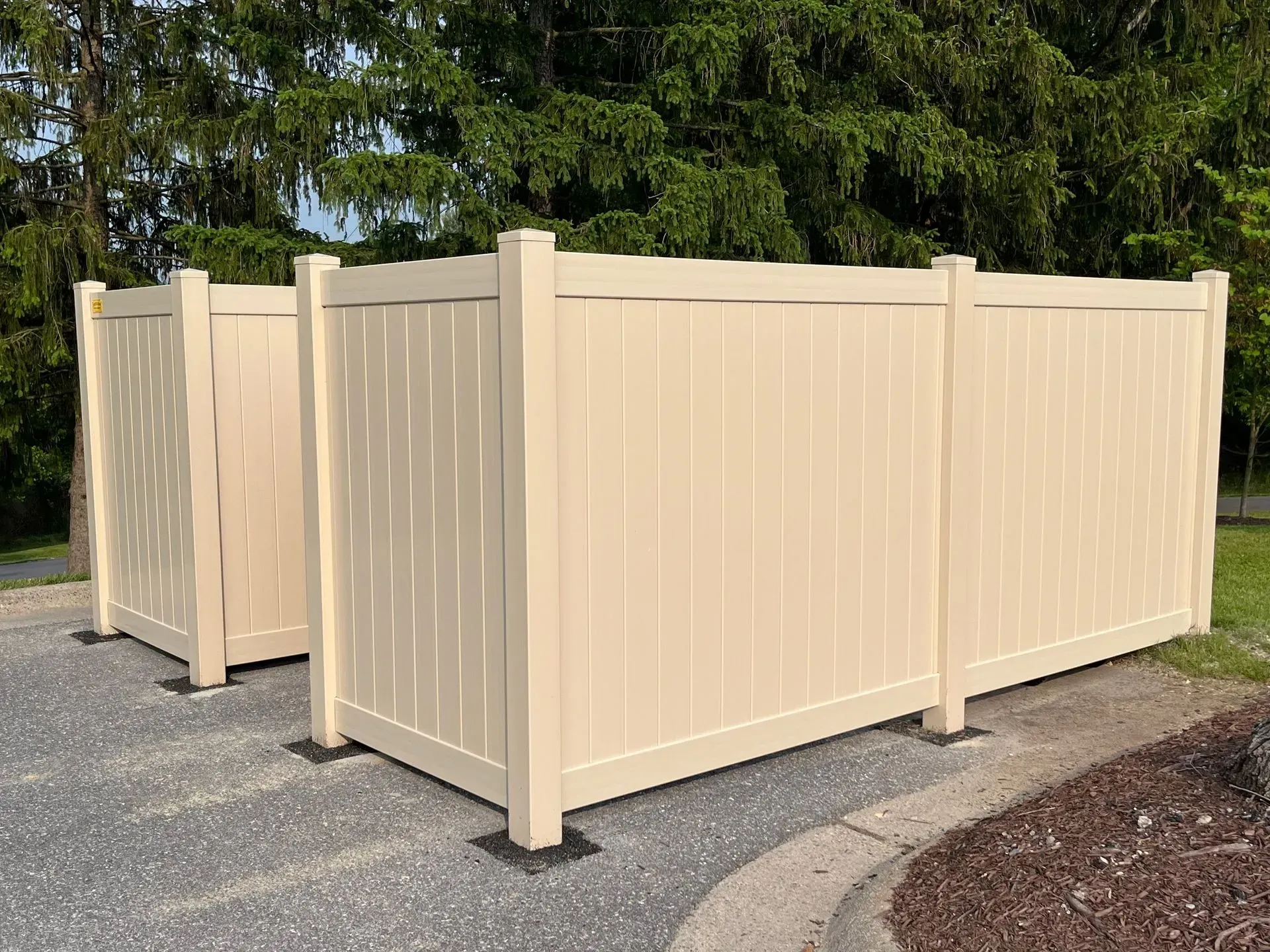 Two white fences are sitting next to each other on a gravel road.