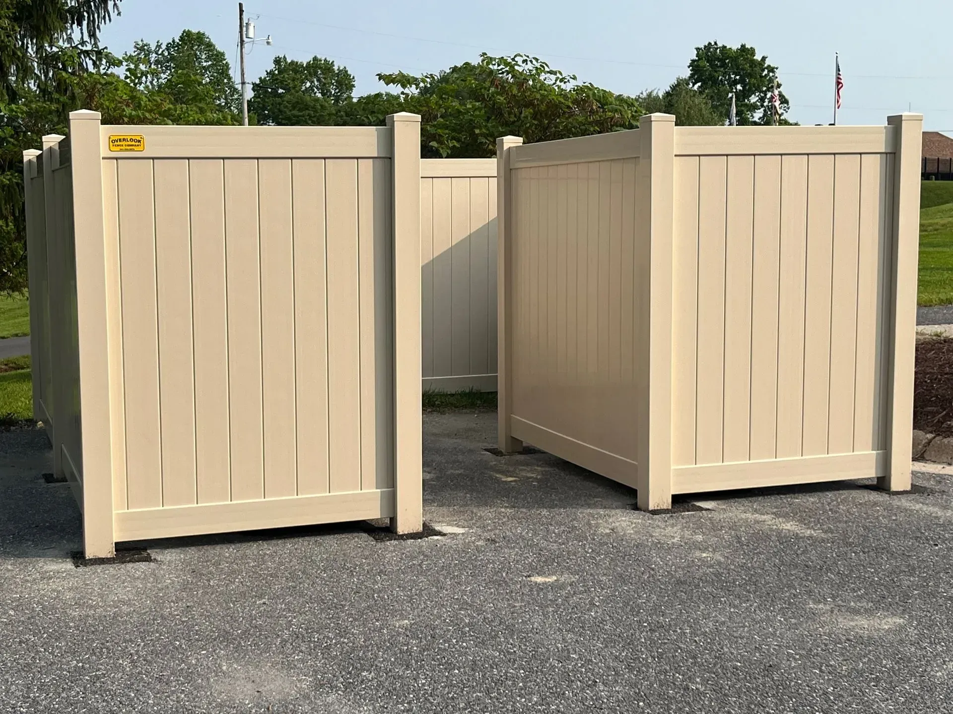 Two white fences are sitting next to each other on a gravel road.