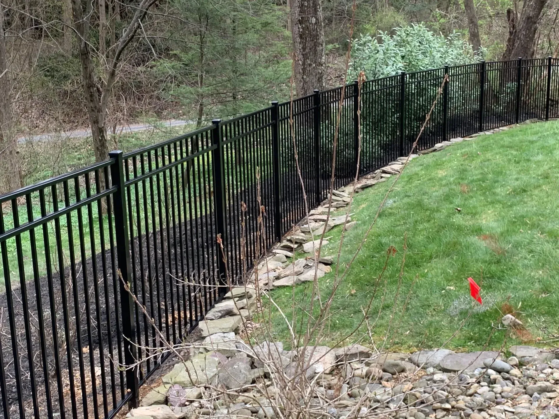 A black metal fence surrounds a lush green lawn.