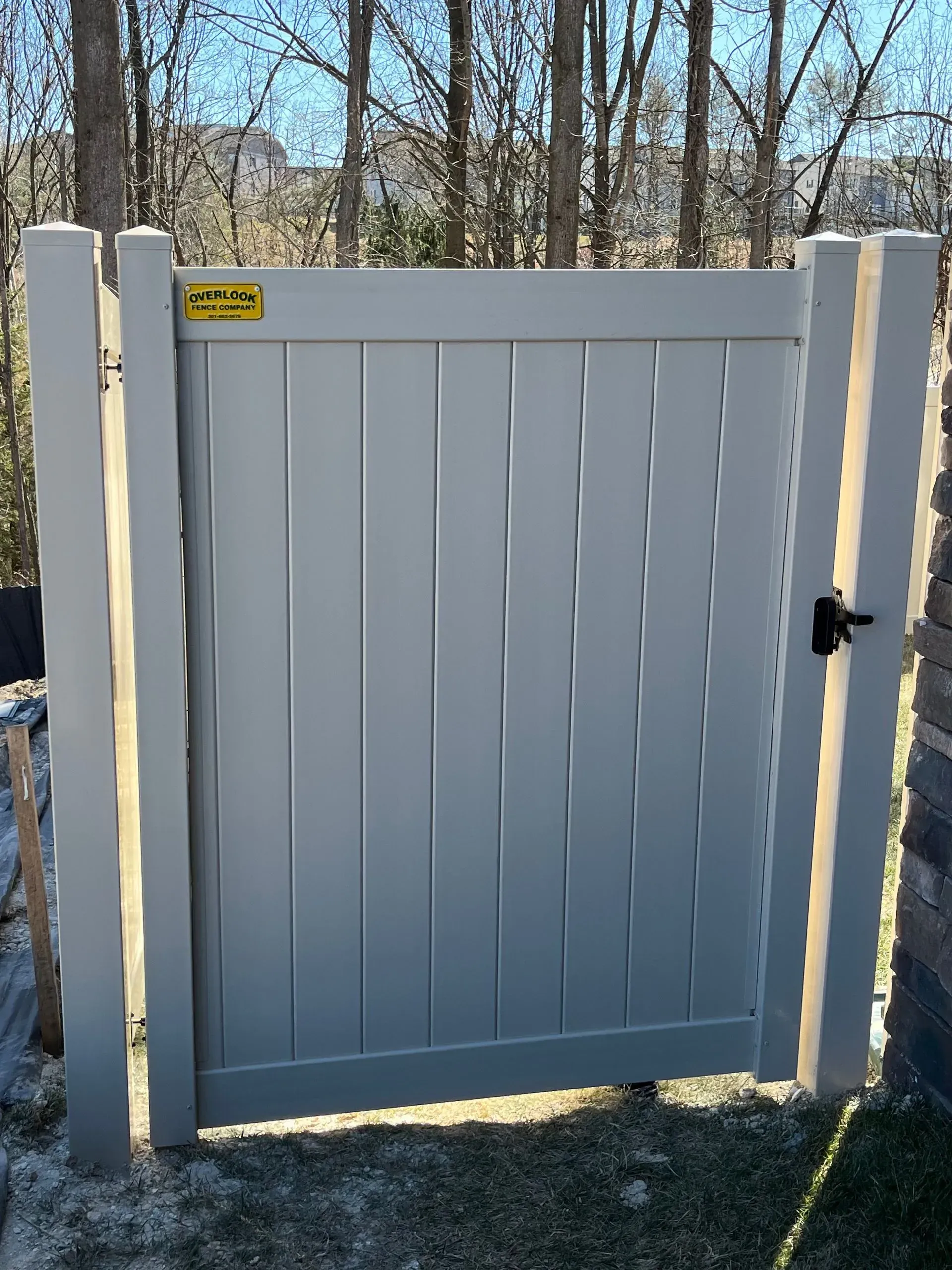 A white gate with a black handle is sitting in the grass.