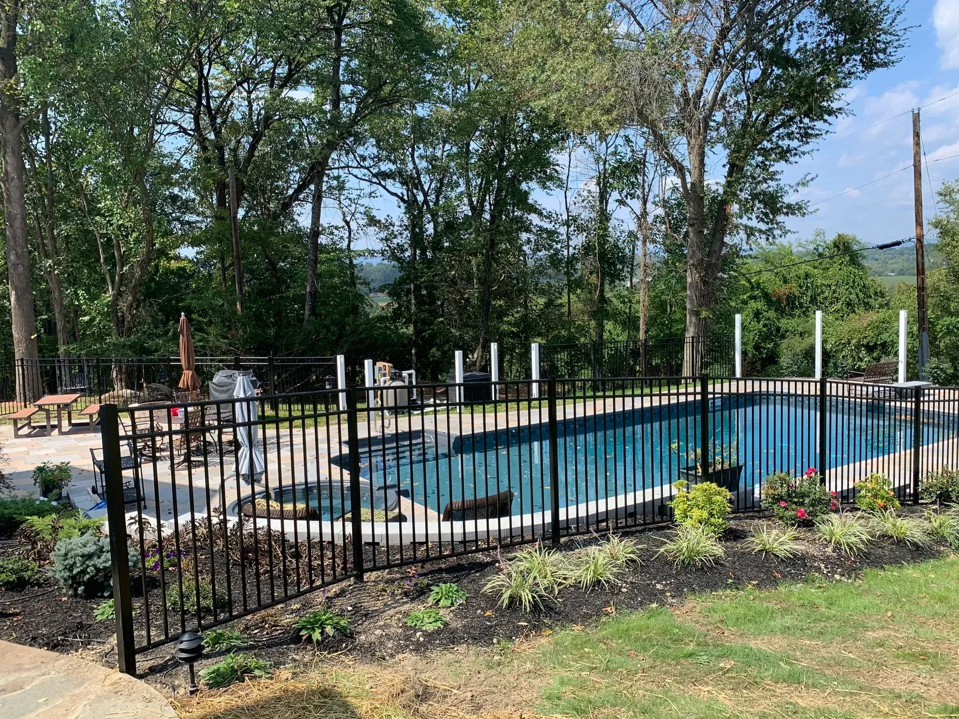 A large swimming pool surrounded by a metal fence in a backyard.
