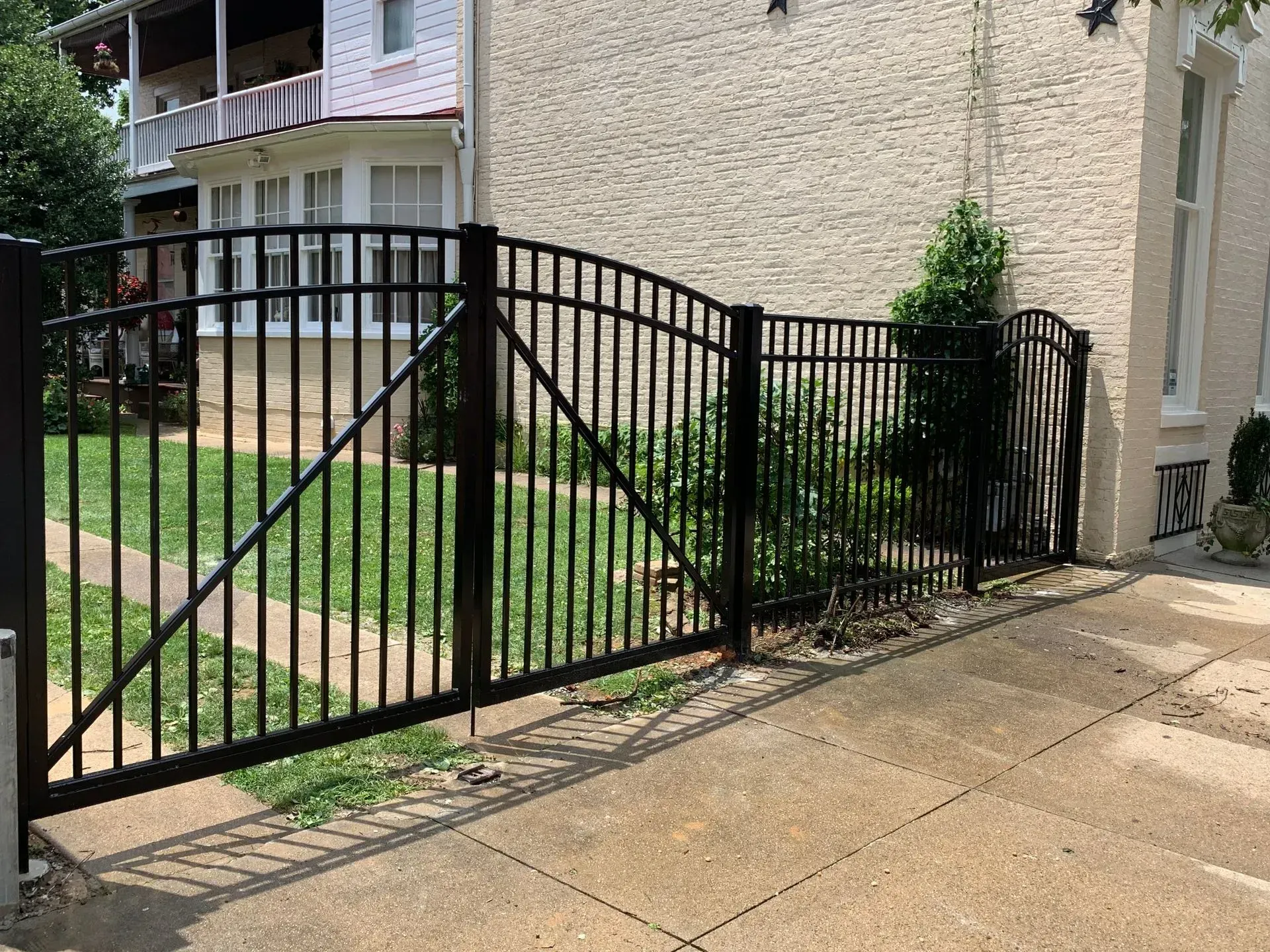 A black fence is in front of a white house.