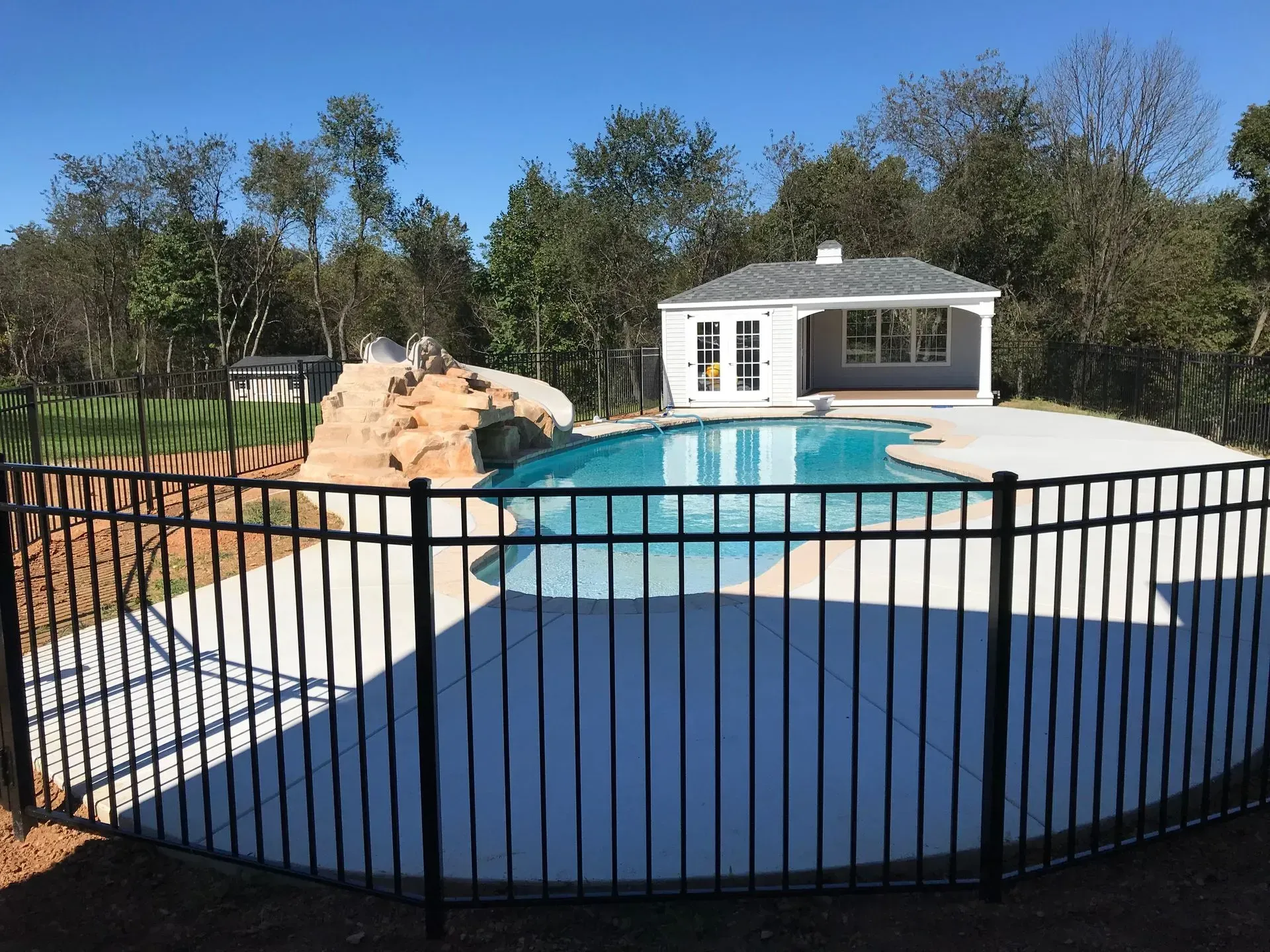 A black fence surrounds a large swimming pool