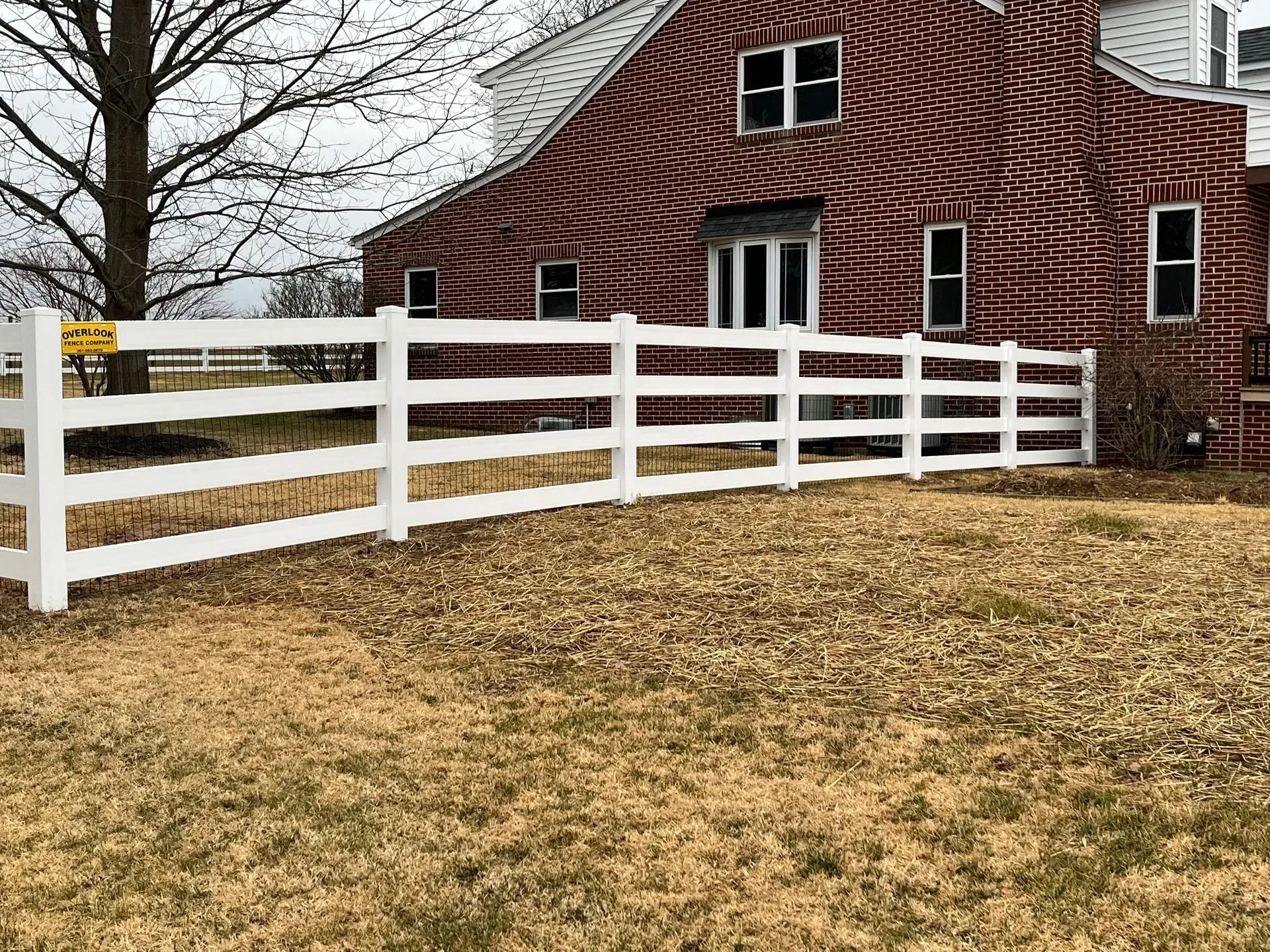 A white fence is in front of a red barn.