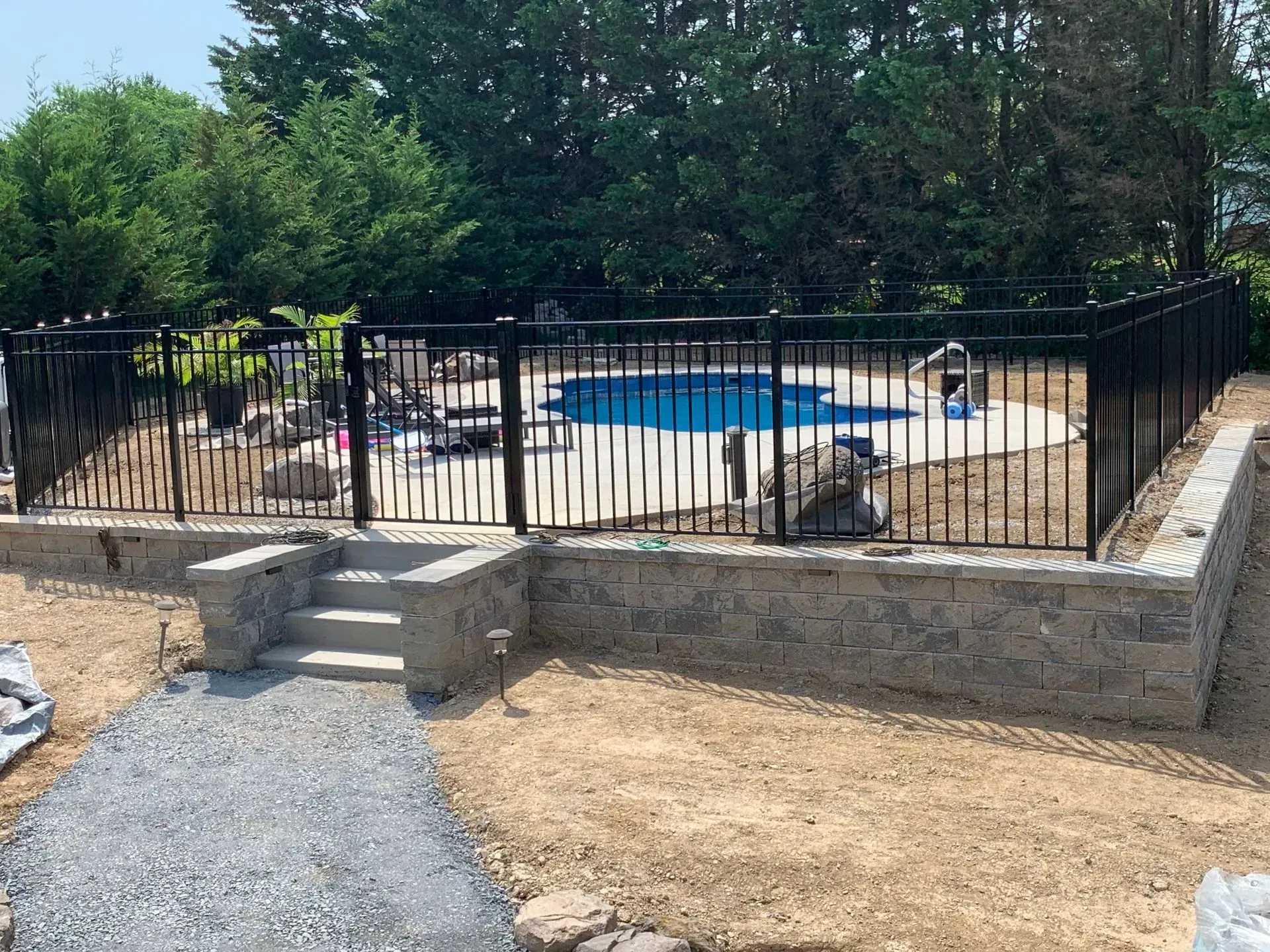 A black fence surrounds a swimming pool in a backyard.