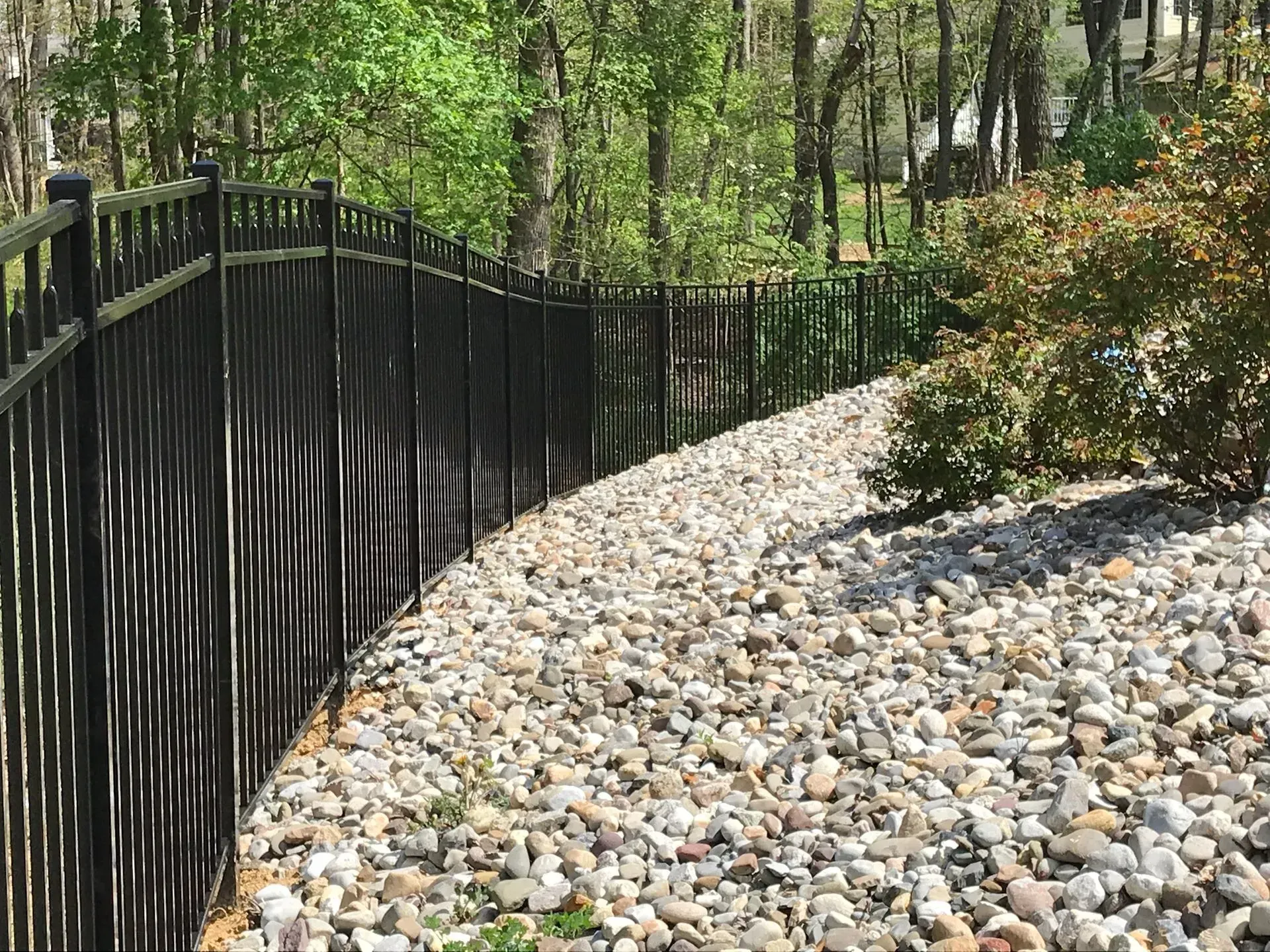 A black fence is surrounded by rocks and trees.